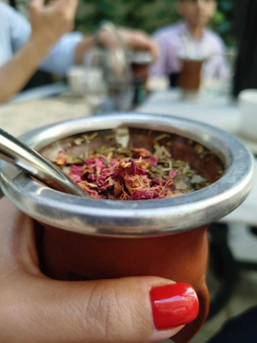 Bowl de yerba con flores y gente con mates de fondo